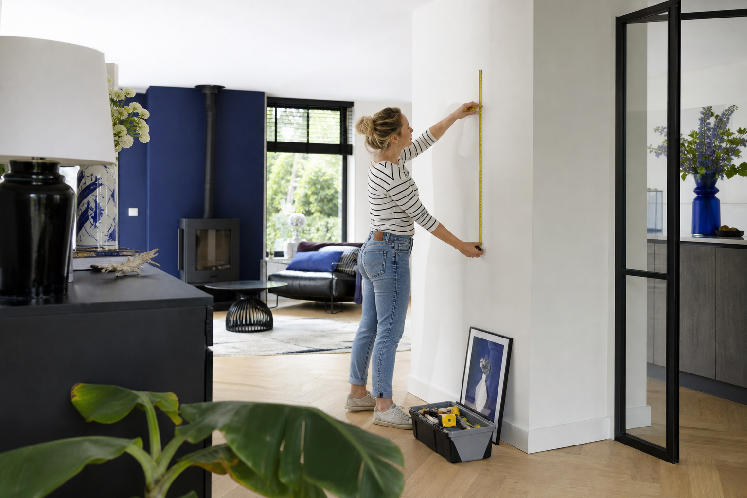 Bewoner meet een lichte muur in een ruim huis met blauwe accenten